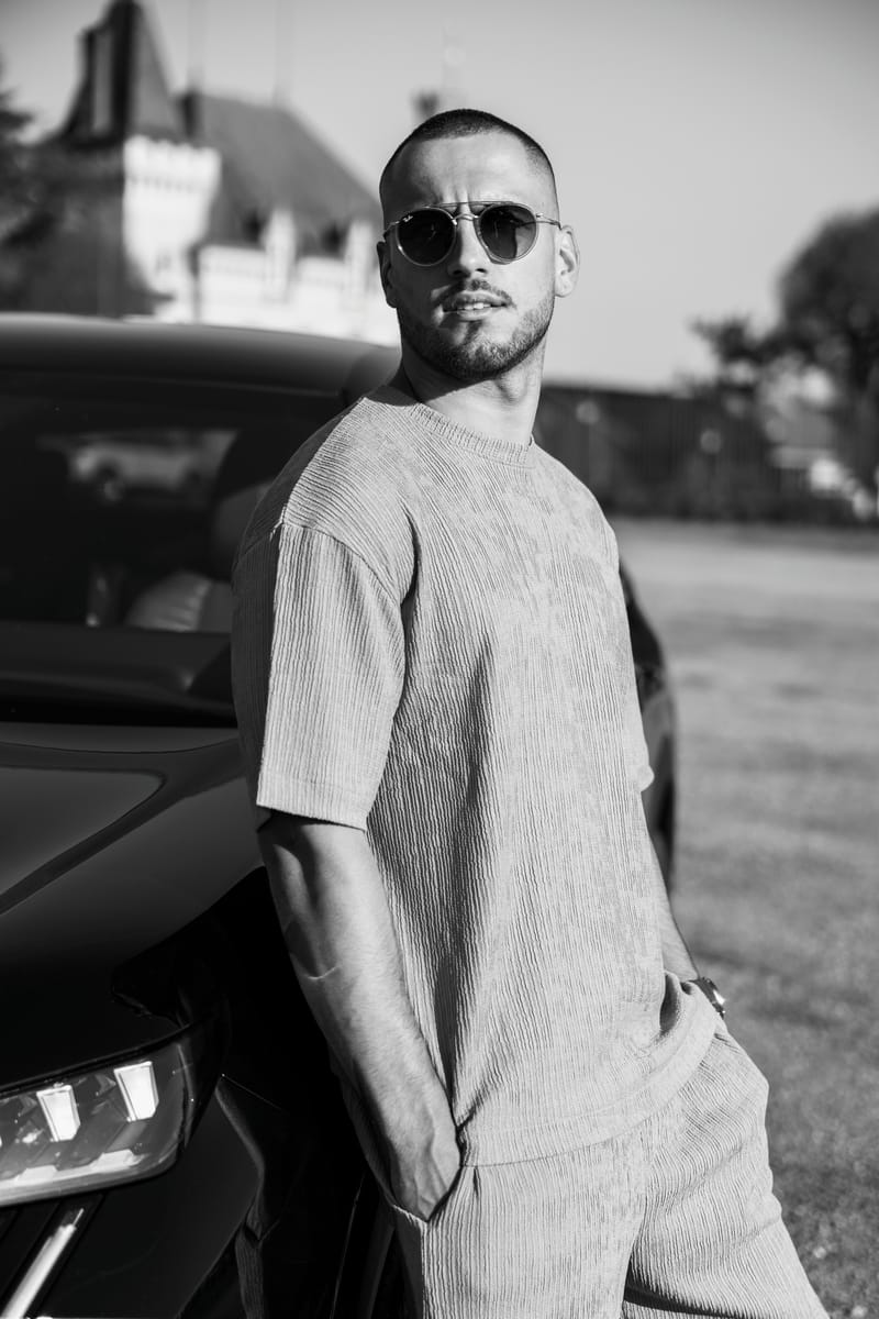 Jeremy Pouch appuyé contre une voiture, en noir et blanc